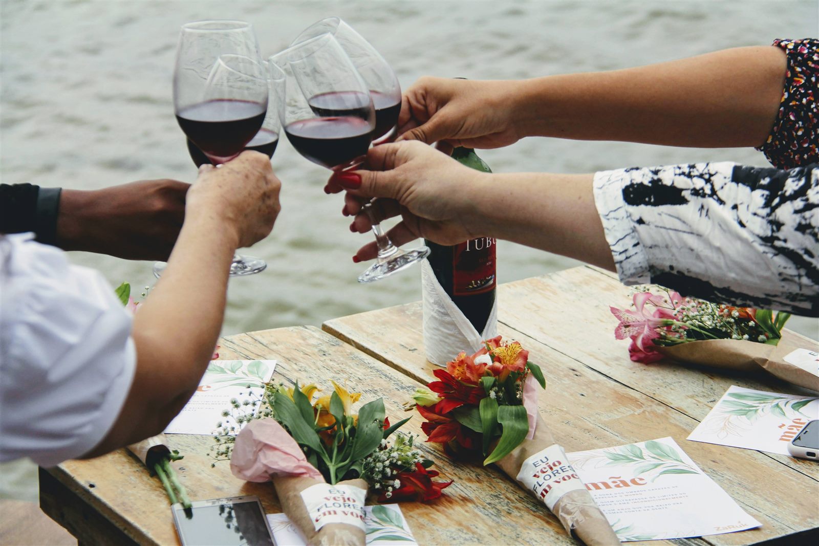 Brinde de taças de vinho com flores, celebração à beira da lagoa